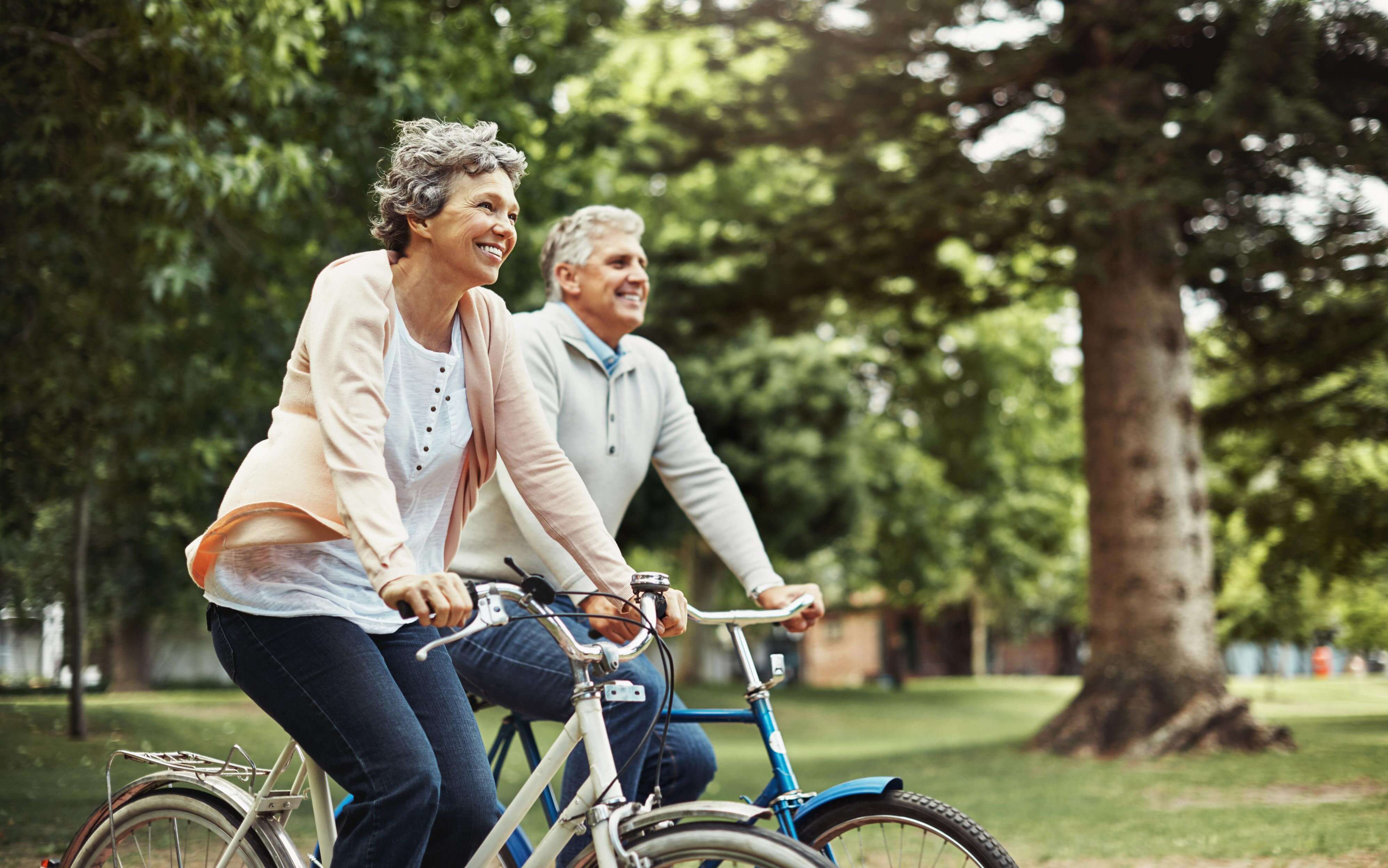 Casal de idosos sorrindo e andando de bicicleta